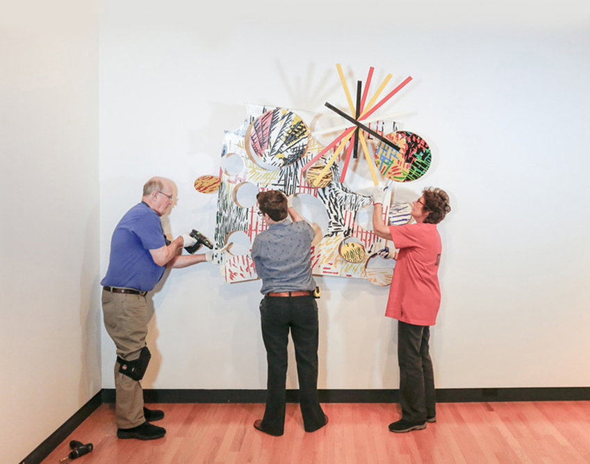 Bob Riddle, Jacqueline Finnegan, and Linda Best install a Judy Pfaff sculpture