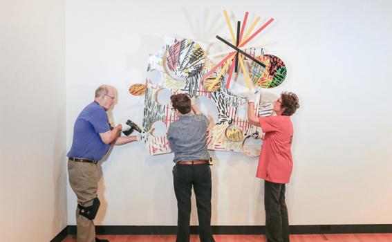 Bob Riddle, Jacqueline Finnegan, and Linda Best install a Judy Pfaff sculpture