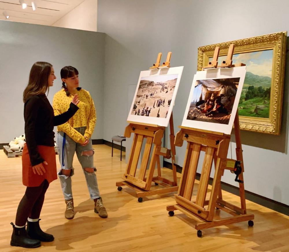 Engagement Intern Charlotte Smith ’24 looking at two photographs by Lynsey Addario.