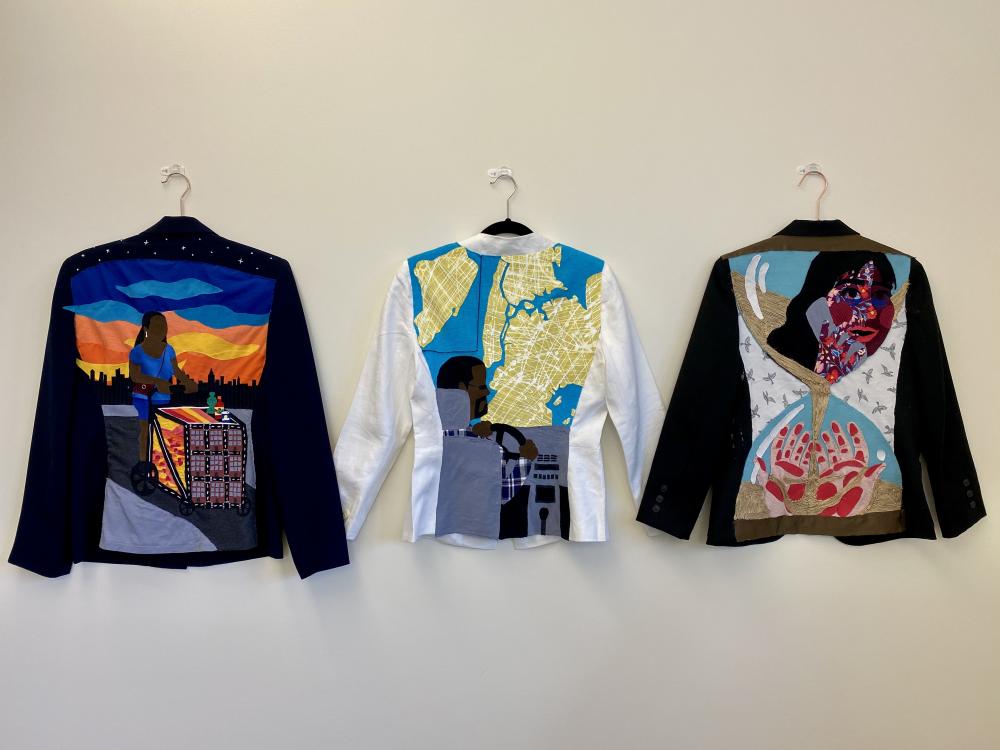 Jennifer Villa ’21, "Upon my back" series overview (2021). Fabric on blazers. 26 x18 in. The backs of 3 decorated blazers hung side by side.