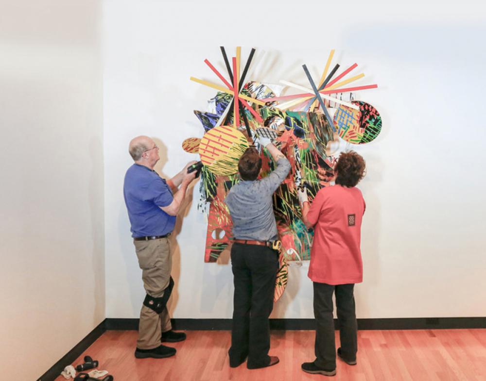 Bob Riddle, Jacqueline Finnegan, and Linda Best install a Judy Pfaff sculpture