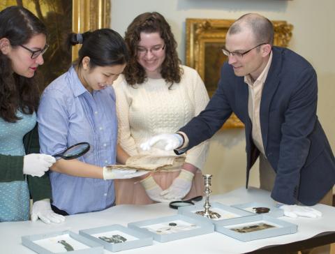 Professor Desmond Fitz-Gibbon and students in the History of Money course examine money-related objects at MHCAM.