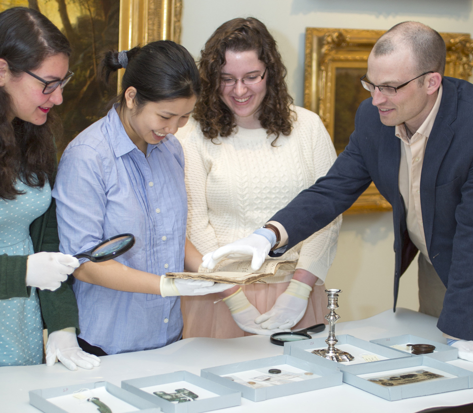 Students in History of Money, Spring 2024, Professor of History Desmond Fitz-Gibbon and students , Students examine various forms of money from the Art Museum and Skinner Museum collections
