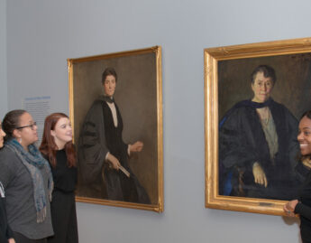 Student tour guides discuss portraits of Mary Woolley