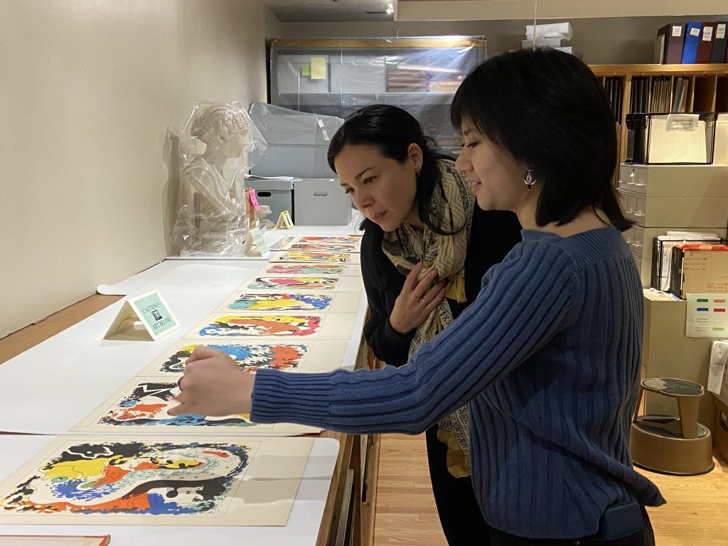 Two people look over a set of prints on a table