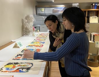 Two people look over a set of prints on a table